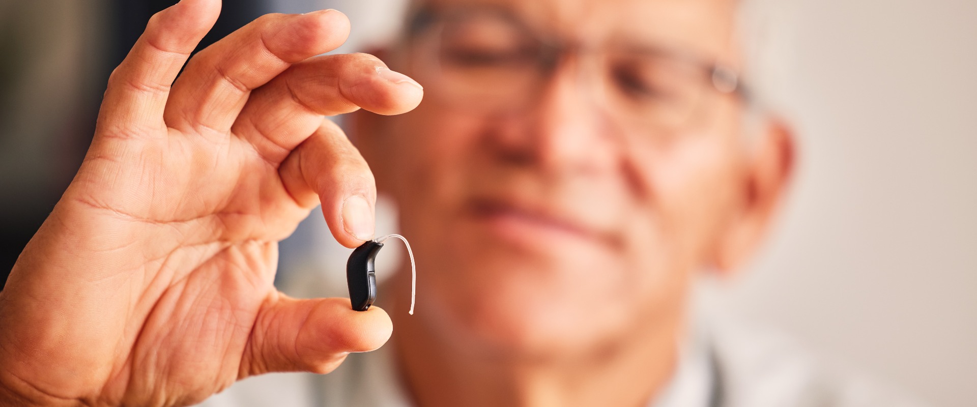 Ein älterer Herr, der ein Hörgerät in der Hand hält, sowie Technik für die Ohren, Gesundheit und Wohlbefinden im Ruhestand in einem Pflegeheim. Eine ältere Person mit Behinderung, Audio- oder Tontechnik, um zu Hause genau hinzuhören