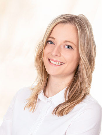 Frau laechelt, blondes Haar, weisse Bluse, Gesicht unscharf markiert